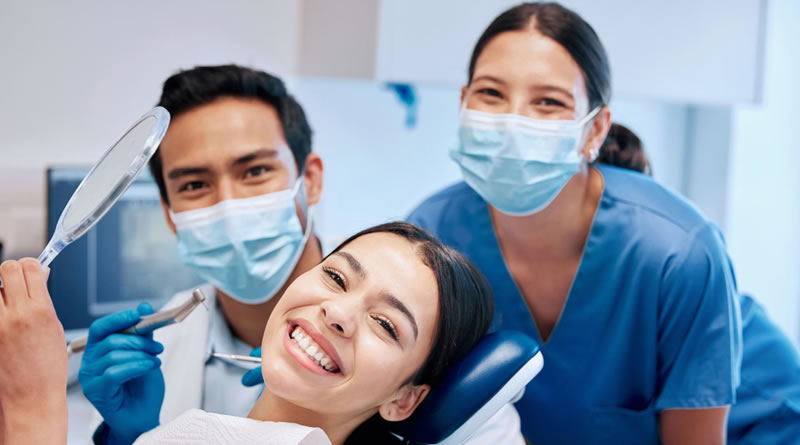 Dentista sorrindo com paciente em clínica odontológica moderna.
